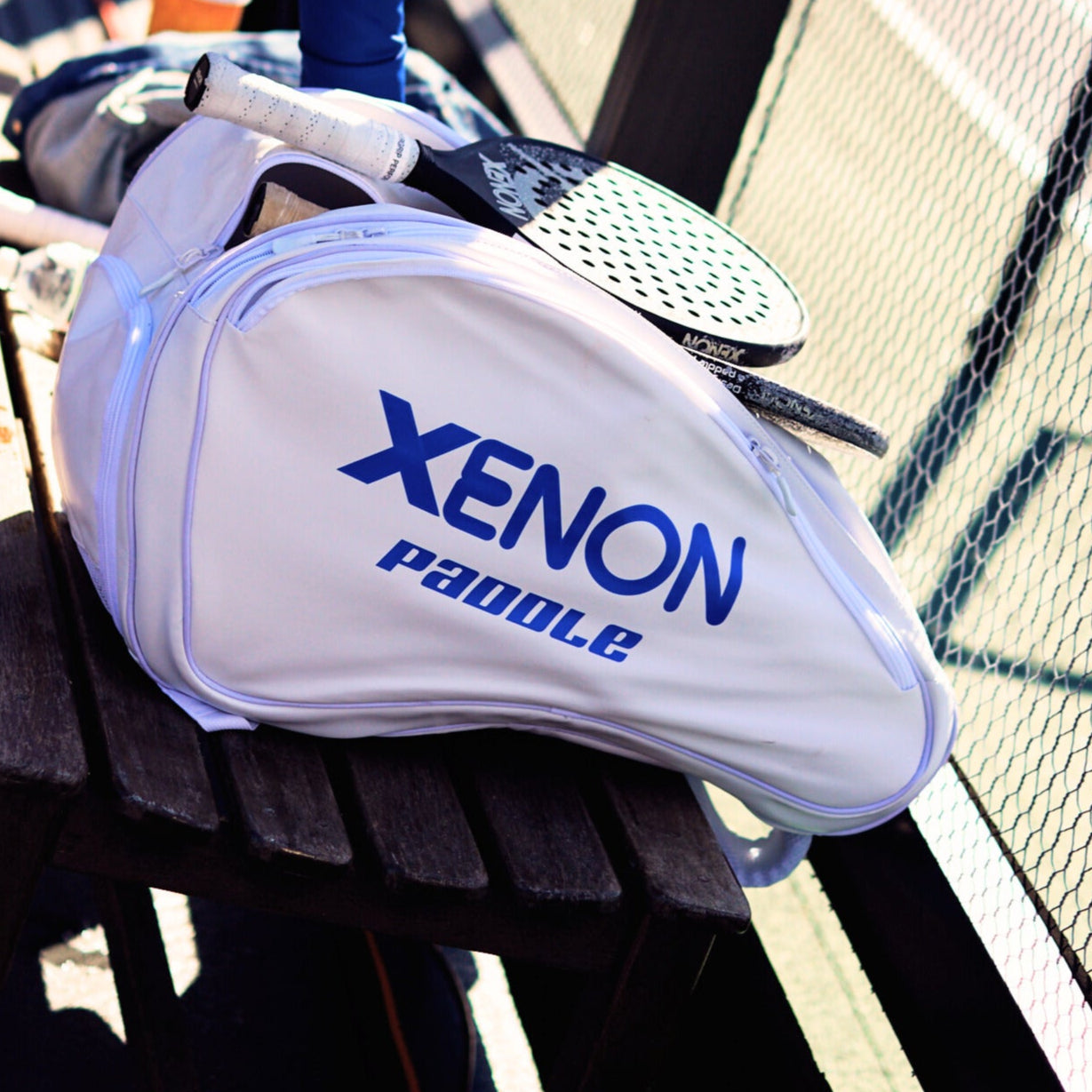 Our white Xenon paddle bag placed on a bench with Xenon paddles and other materials being stored inside of it.