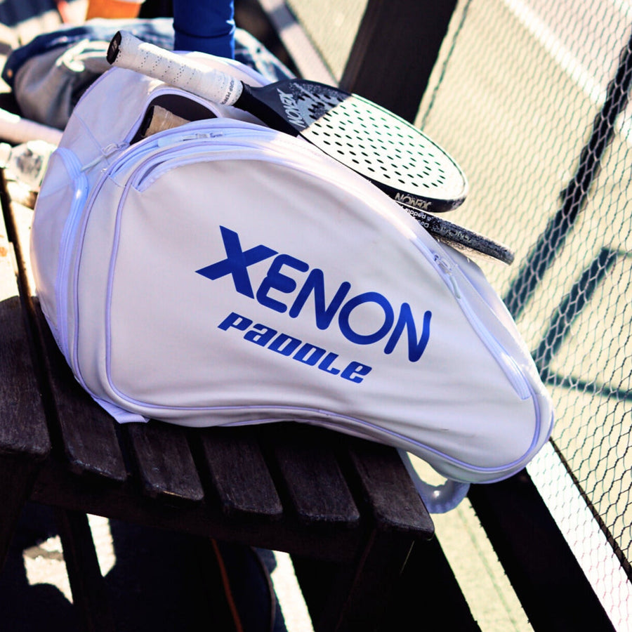 Our white Xenon paddle bag placed on a bench with Xenon paddles and other materials being stored inside of it.